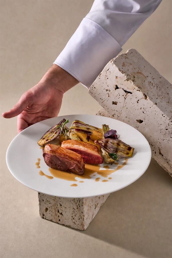 Petto d'anatra scottato con radicchio grigliato e arancia su travertino, fotografia food per ristoranti a Milano
