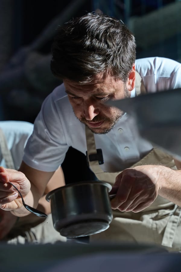 Chef in grembiule che assaggia dalla pentola in cucina