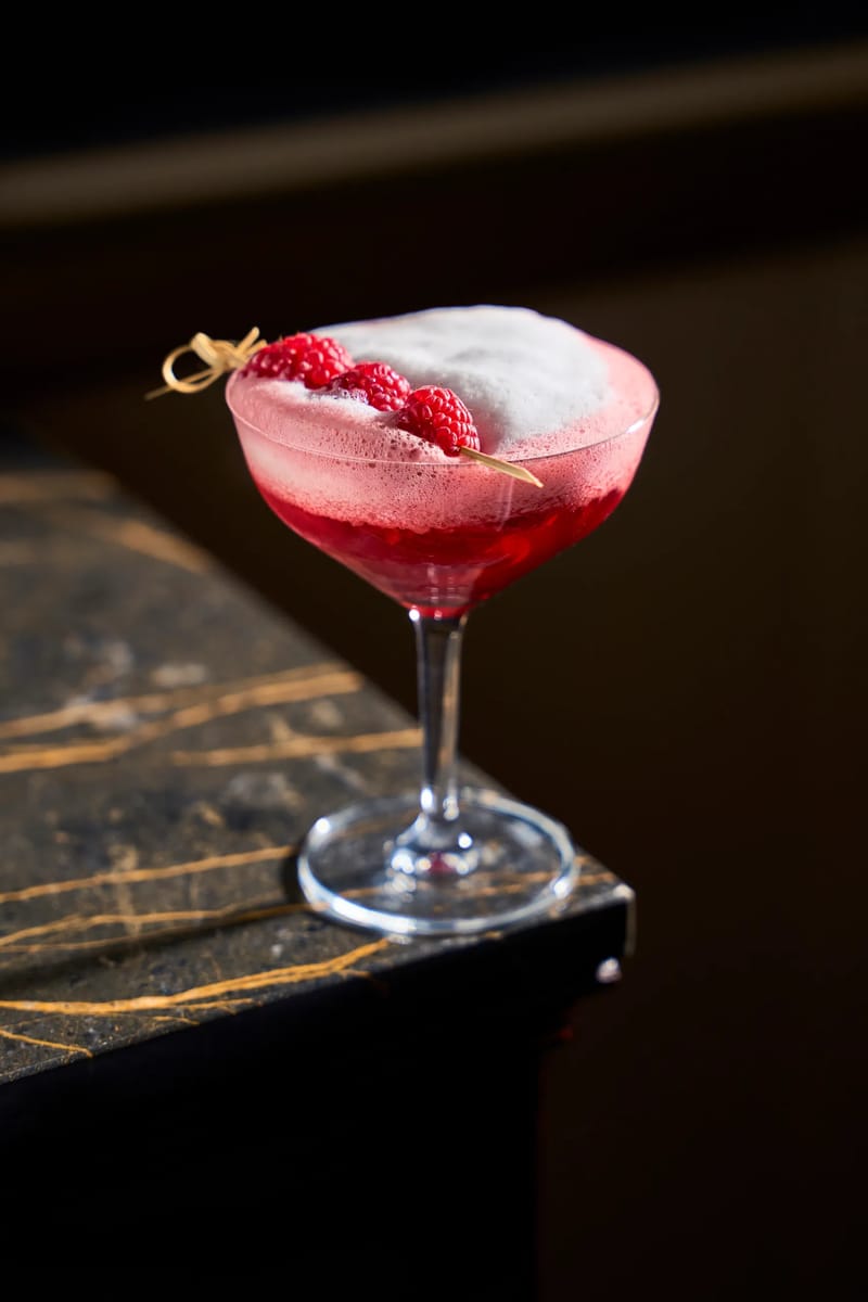 Cocktail ai lamponi con schiuma in coppa martini su marmo nero